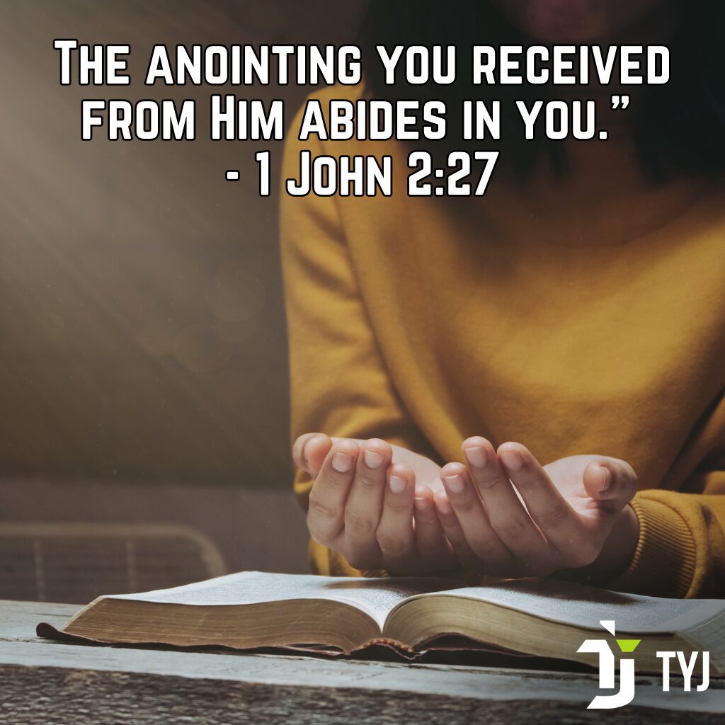 Hands open in prayer over an open Bible reflecting 1 John 2:27 about the anointing you received